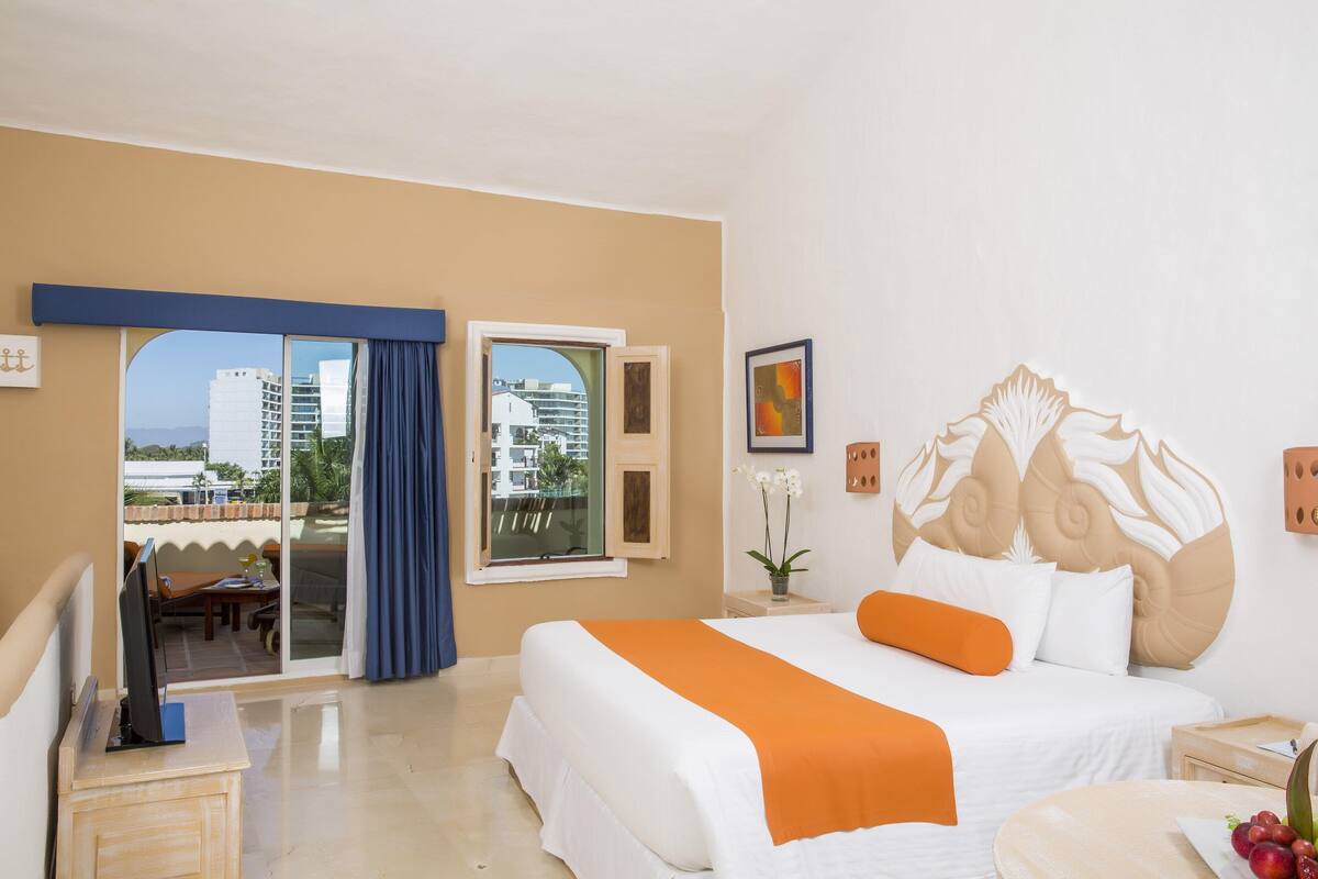 Une chambre d’hôtel avec un grand lit, un bureau et une vue sur la ville, accessible par une porte coulissante.