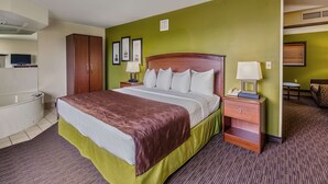 A hotel room with a bed, a nightstand, a lamp, a television, a wardrobe, and a bathroom. - AmericInn by Wyndham Wahpeton (Wahpeton)