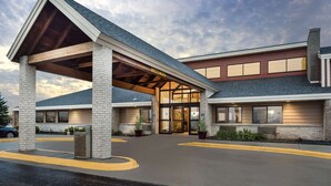 A hotel entrance with a covered walkway, brick facade, and a clear sky. - AmericInn by Wyndham Wahpeton (Wahpeton)