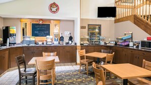 A coffee shop interior with wooden furniture, a chalkboard sign, and a staircase. - AmericInn by Wyndham Wahpeton (Wahpeton)