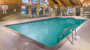 An indoor swimming pool with clear safety signage, a wooden interior, and a view of the outdoors through large windows. - AmericInn by Wyndham Wahpeton (Wahpeton)