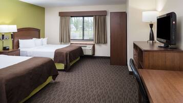 A hotel room with two beds, a desk, a television, and a window with curtains.
