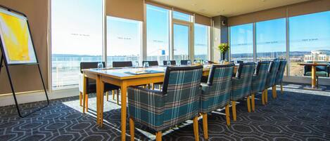 A conference room with a large table, chairs, and a view of the city through large windows.
