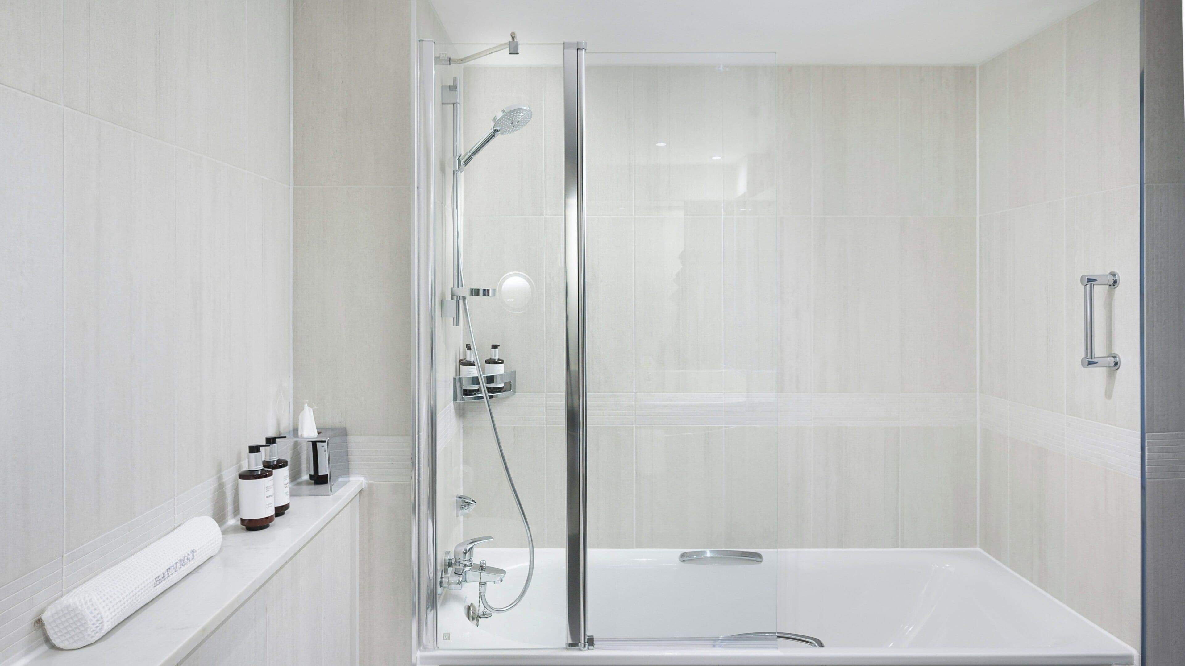 A modern bathroom with a glass-enclosed shower, a bathtub, and a shelf with toiletries.