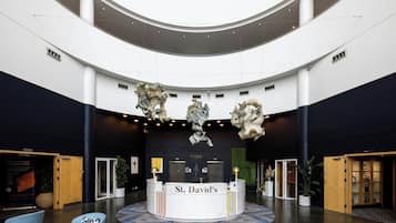 A lobby with a reception desk labeled 'St. David's,' a staircase, and a large, circular ceiling design.