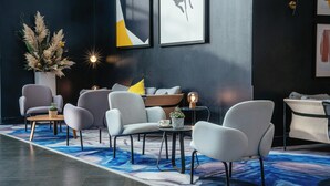 A modern lounge area with seating, a coffee table, and a decorative plant. - voco St David's Cardiff by IHG (Cardiff)