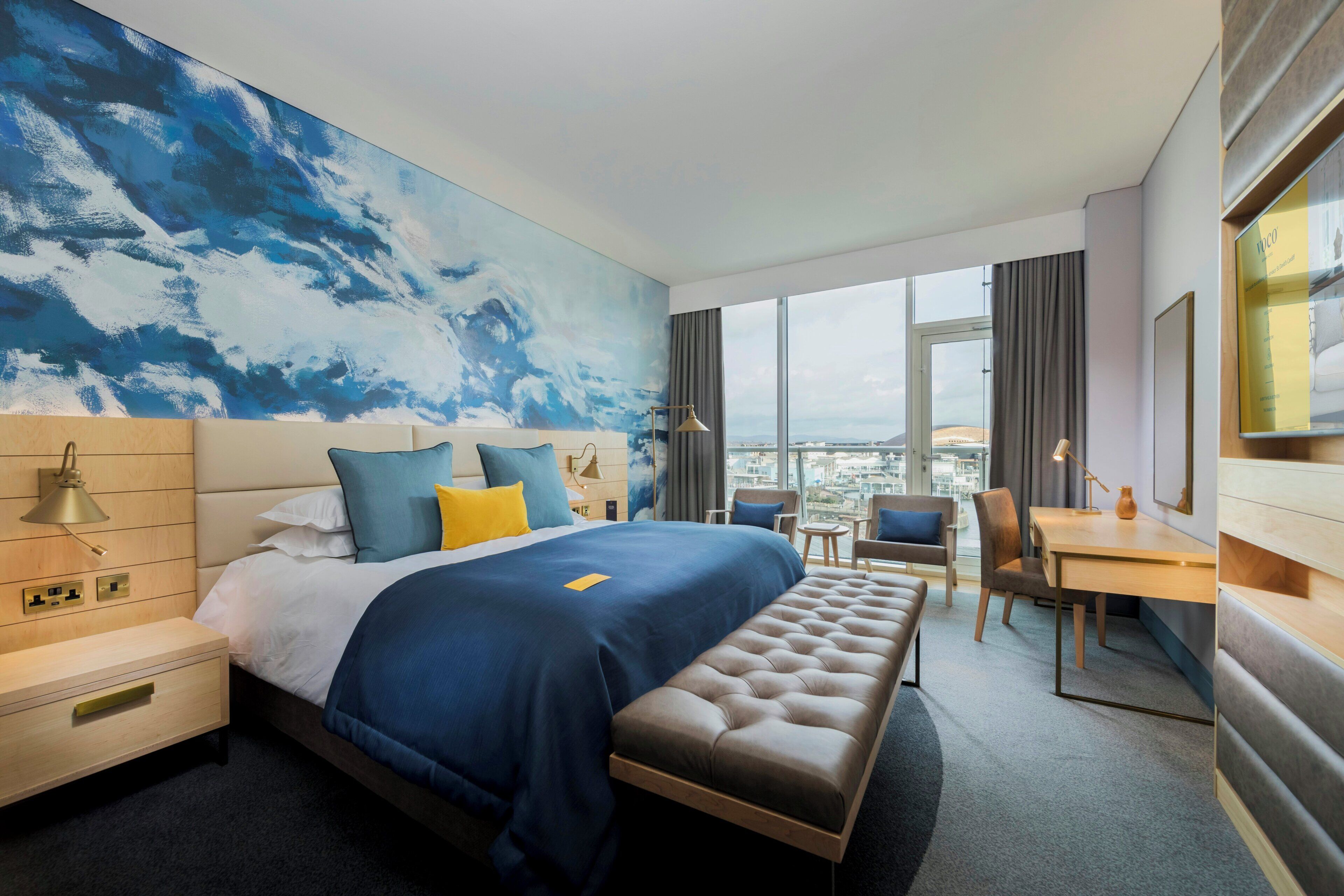 Une chambre d’hôtel moderne avec un grand lit, un bureau et une vue sur la ville.