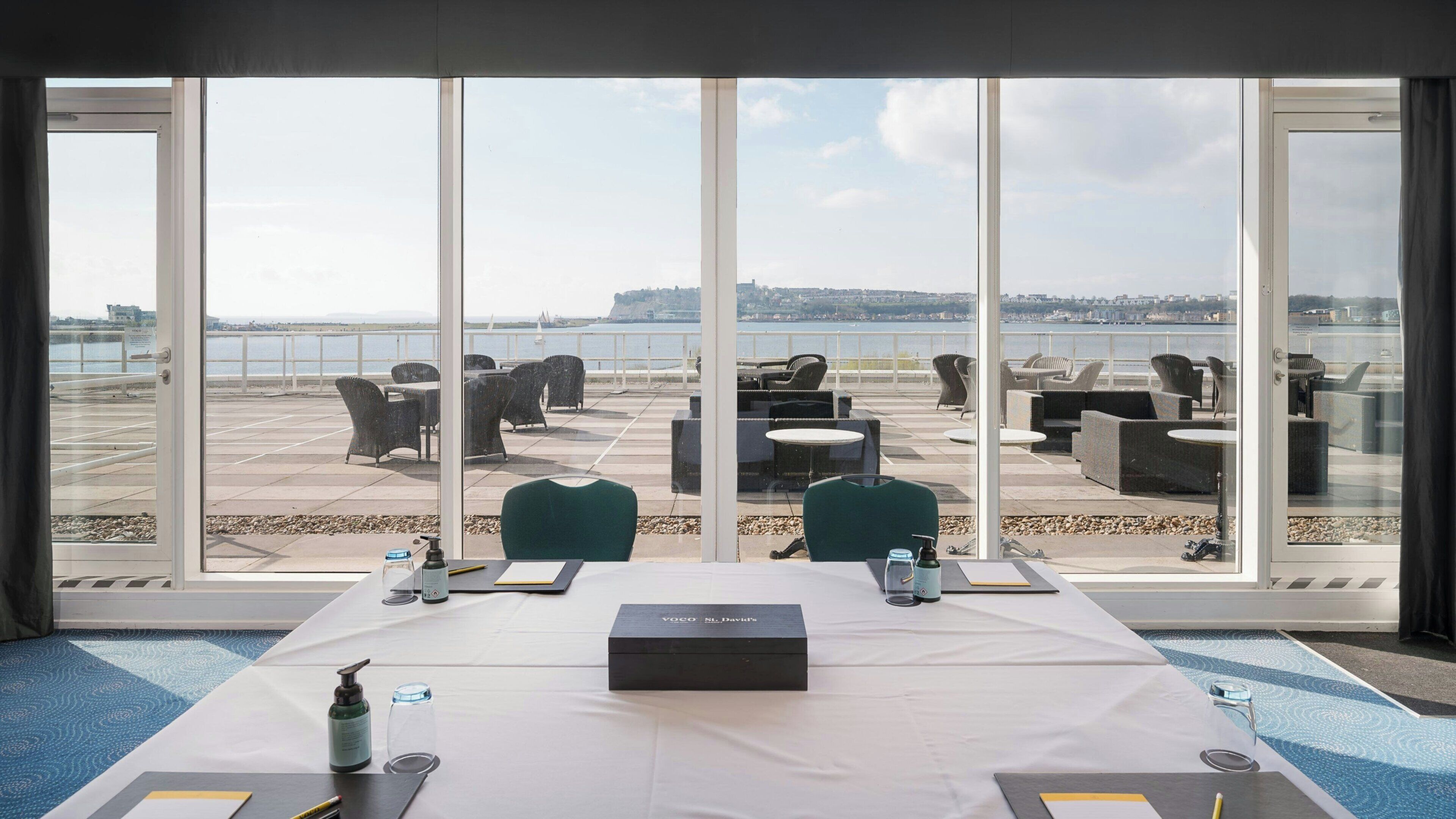 A conference room with a table, chairs, and a view of a waterfront.