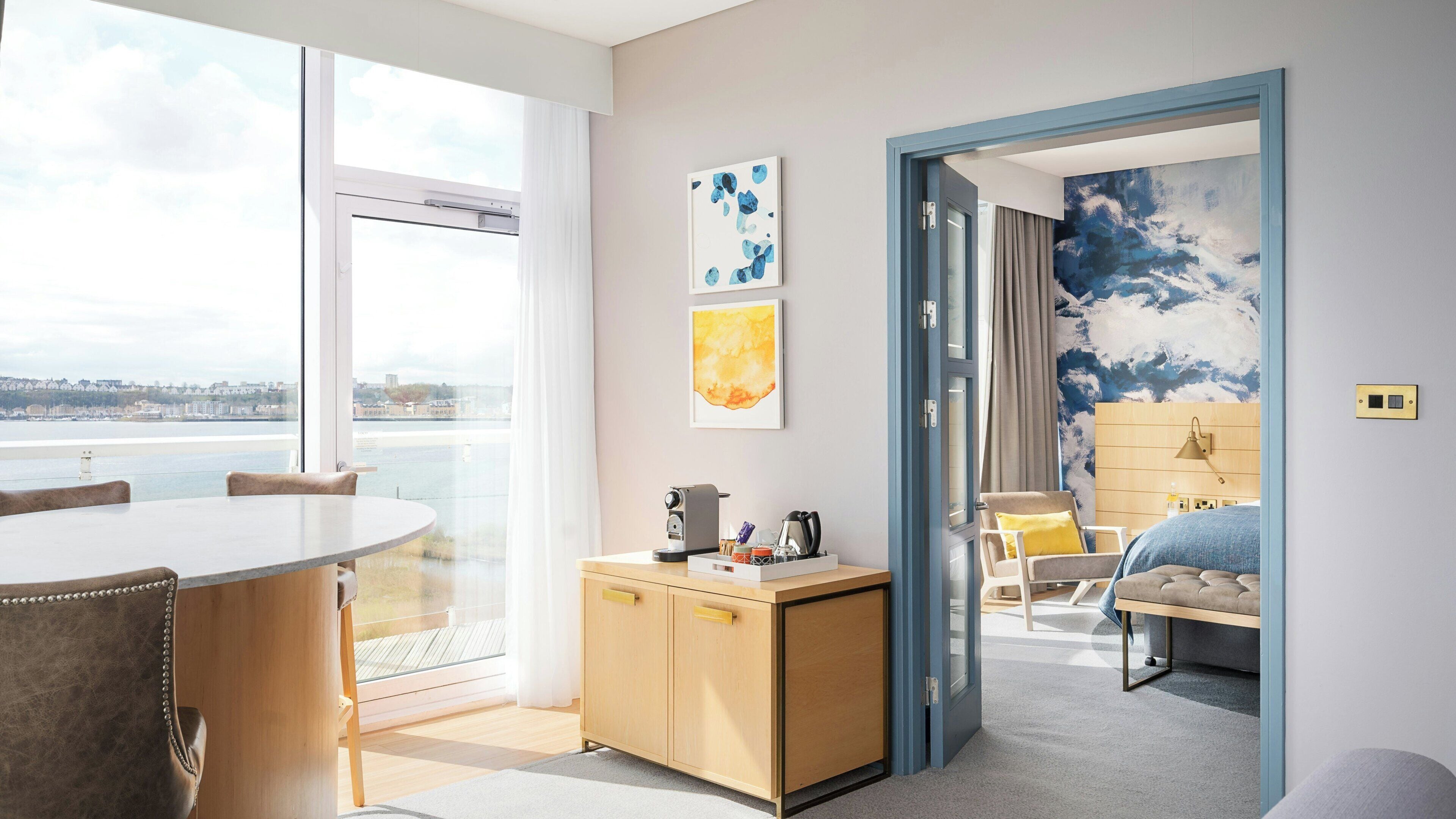 Una habitación de hotel moderna con balcón, zona de comedor y dormitorio.