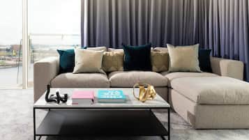 A modern living room with a sectional sofa, a coffee table, and a view of a cityscape through large windows.