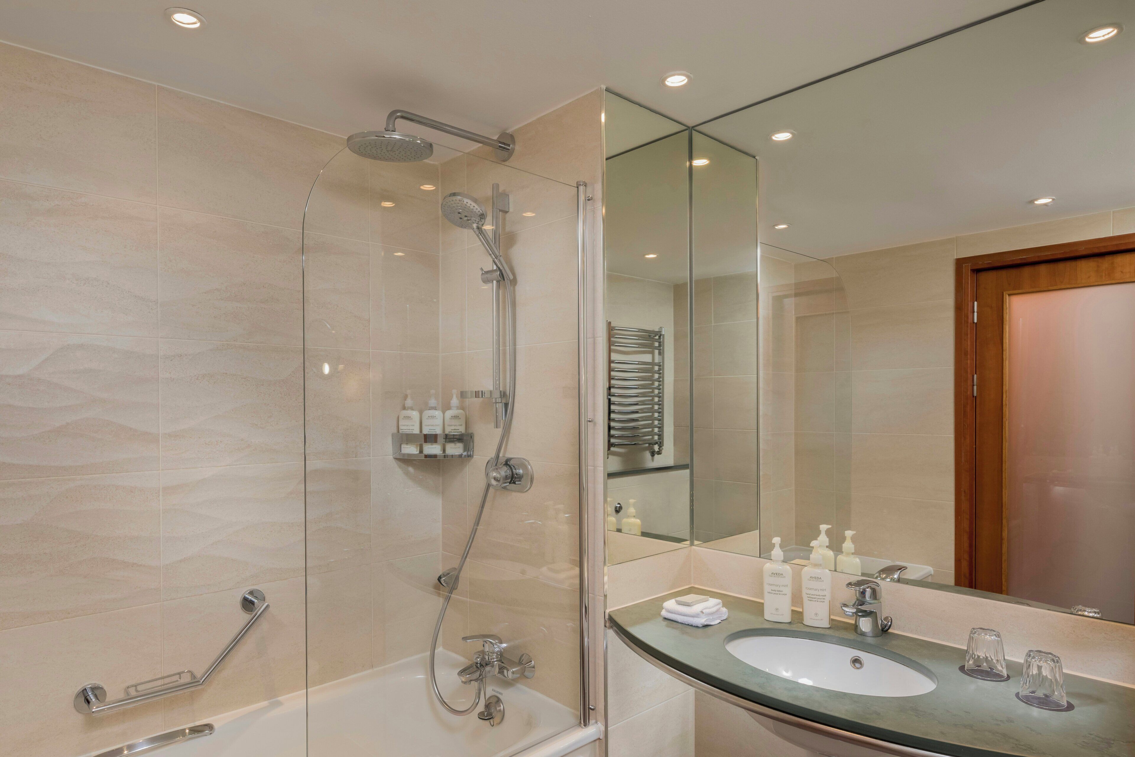 Een moderne badkamer met een douchecabine van glas, een wastafelmeubel en een spiegel.