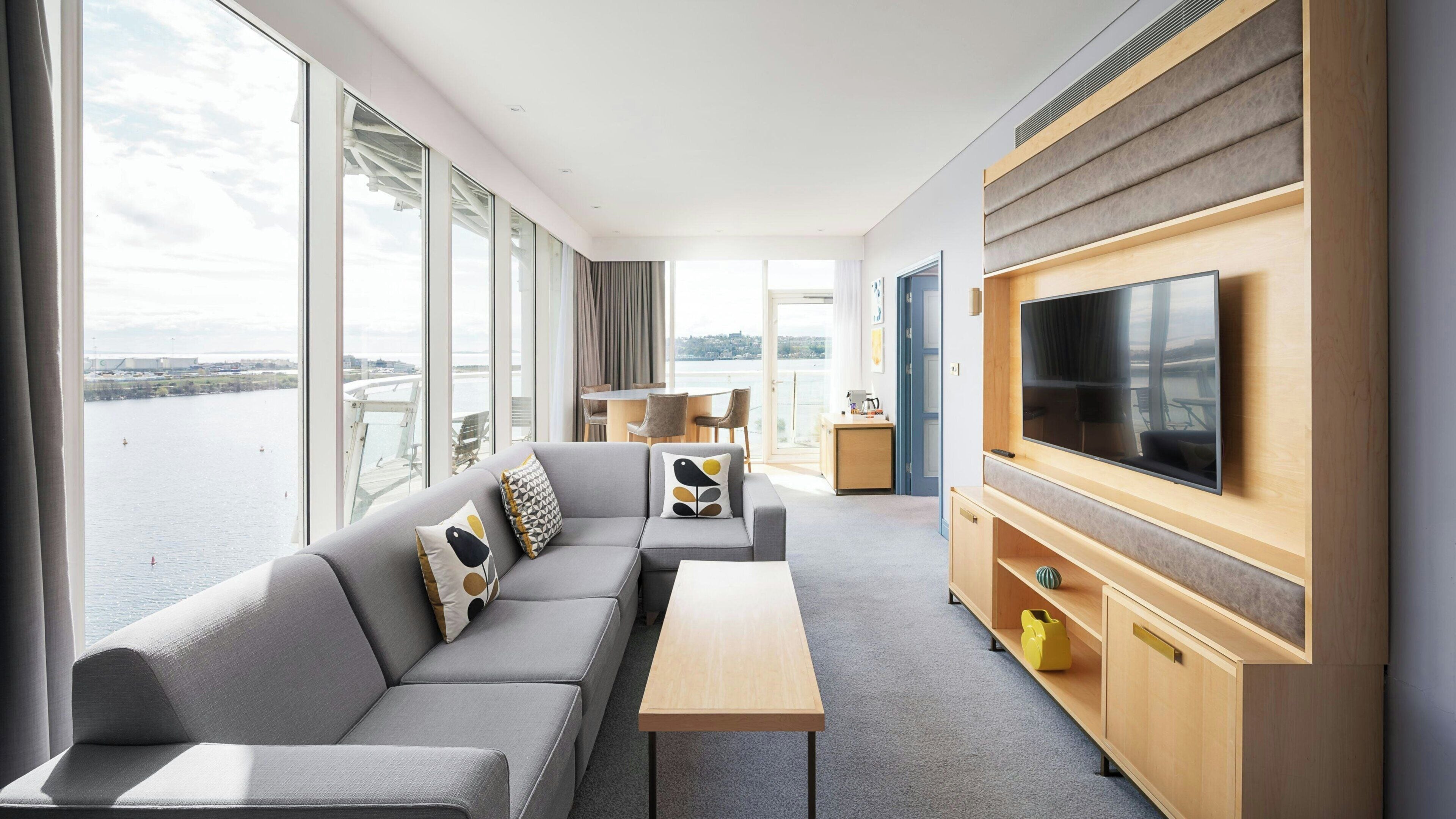 Une chambre d’hôtel moderne avec un canapé, une télévision et une vue sur l’eau.