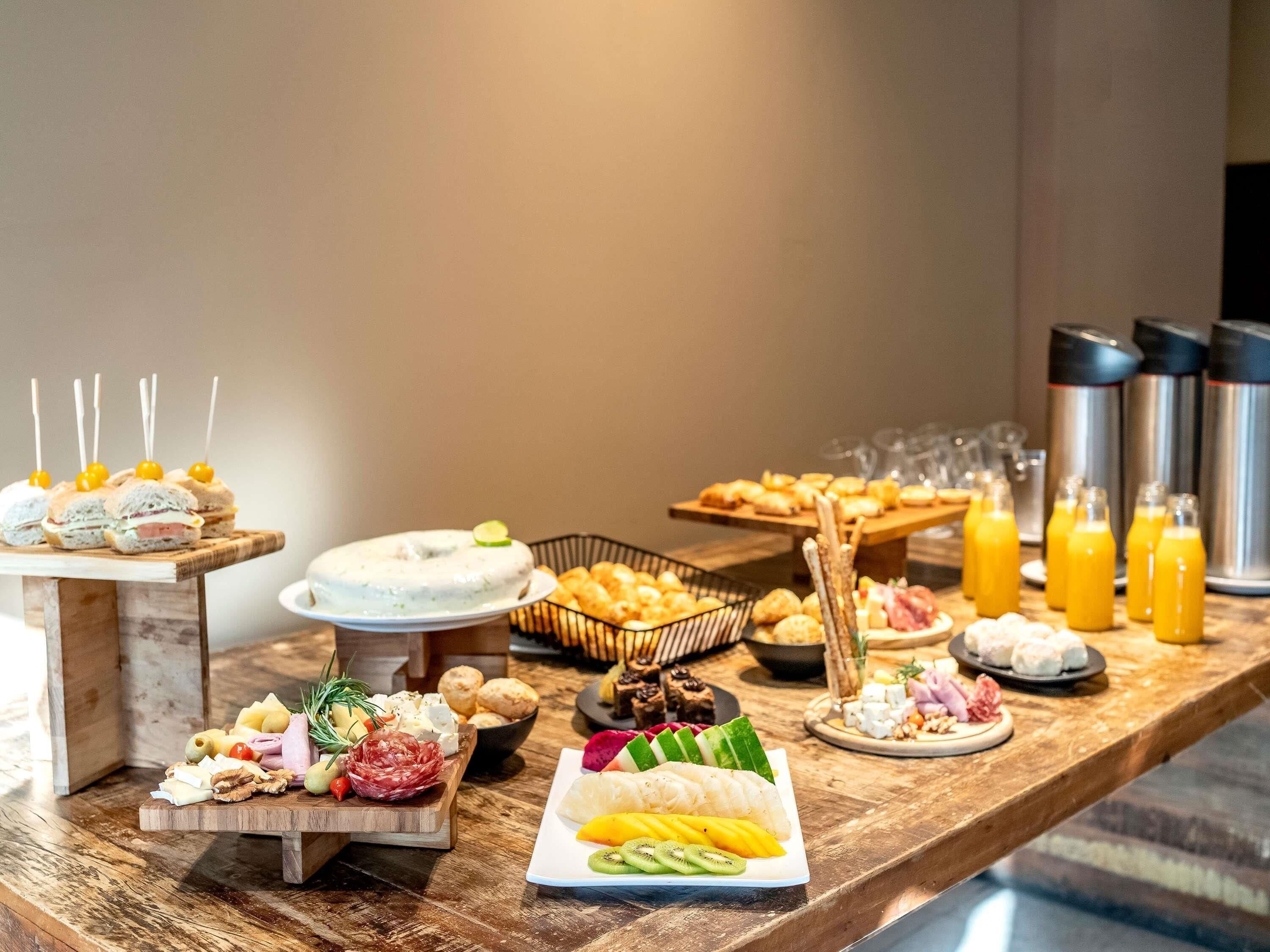 A buffet with various food items, including sandwiches, fruits, cheeses, and meats.