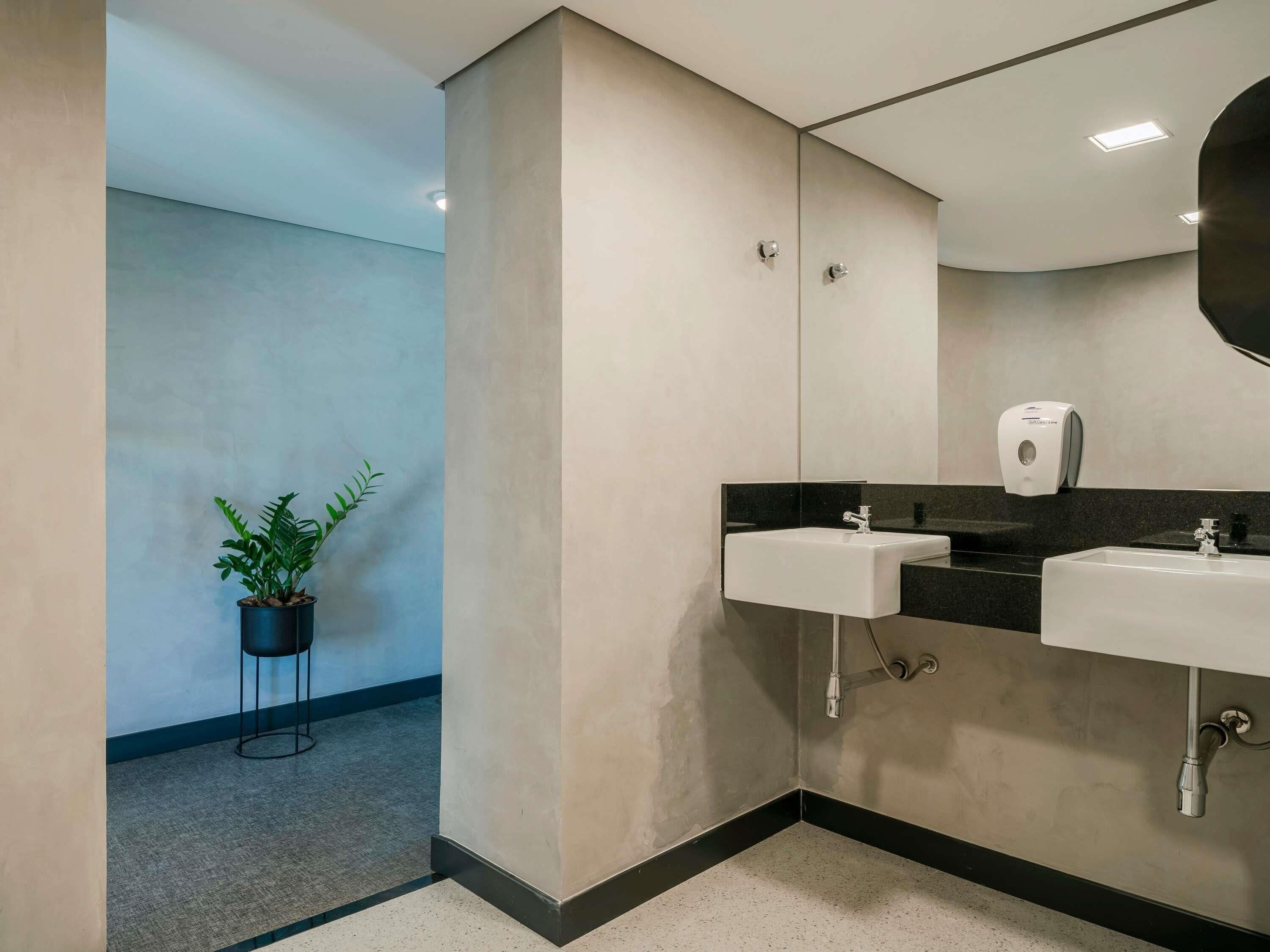 A modern bathroom with a sink, mirror, and hand sanitizer dispenser.