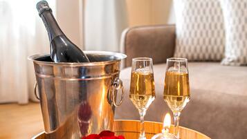 A wooden tray with a champagne bottle, two glasses, and a bowl of red roses.
