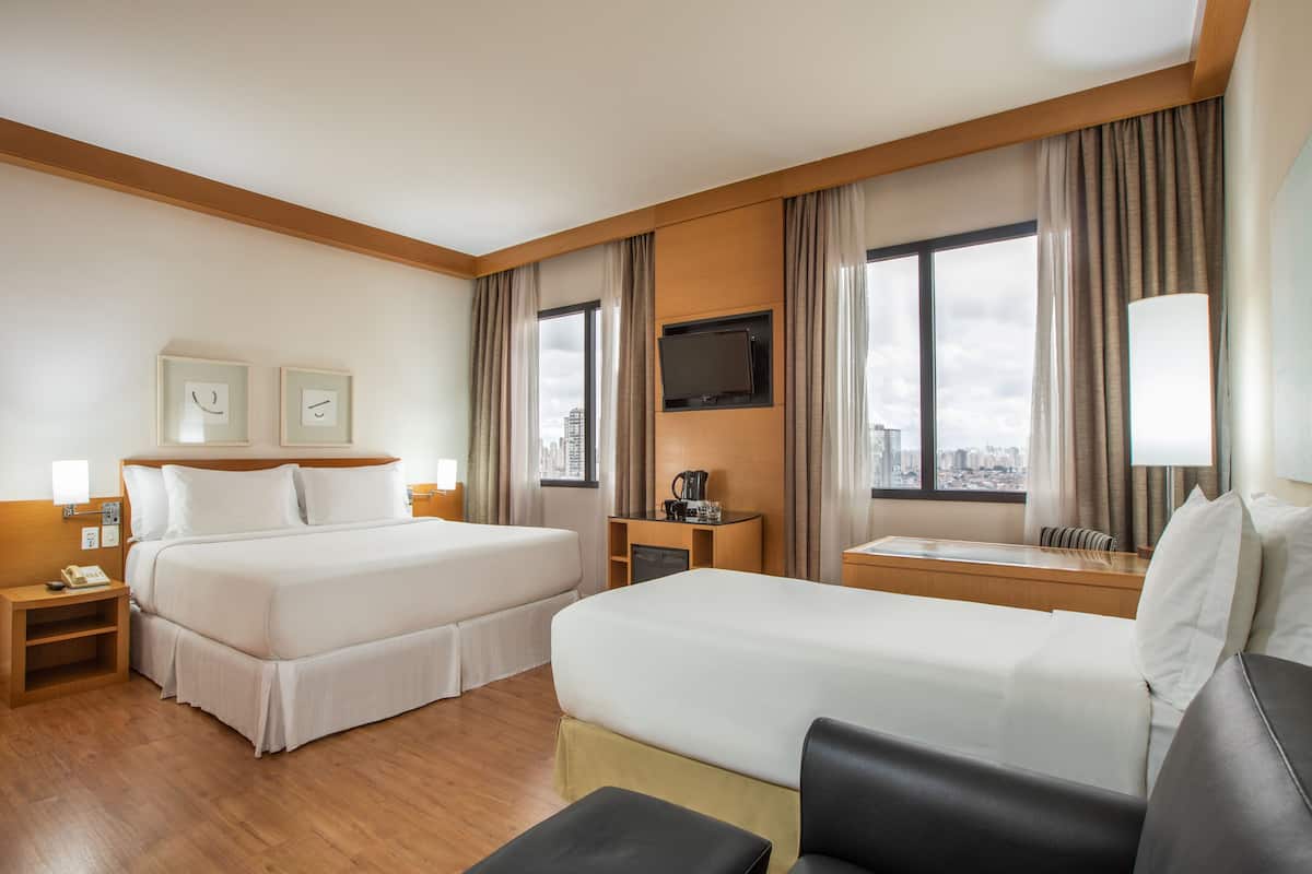 Habitación de hotel con dos camas, televisión, cafetera y vistas a la ciudad.