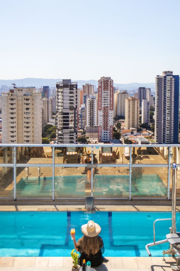 Una piscina al aire libre, sombrillas, sillones reclinables de piscina