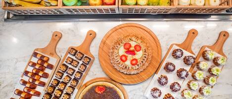 Diversa selección de frutas y postres sobre una encimera de mármol.