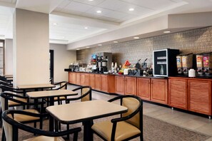 Dine in style with tables and chairs for a comfortable meal, a counter offering a variety of food and beverages, and a coffee machine.