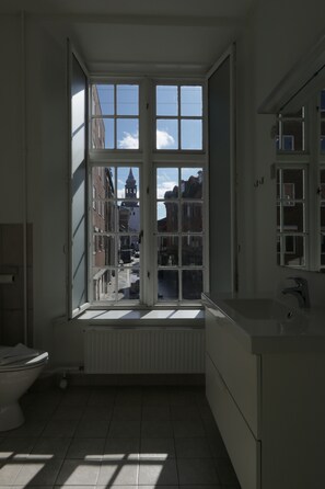 A bathroom with a large window, a toilet, and a sink. - Hotel Phønix (Aalborg)