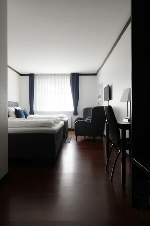 A hotel room with a bed, a desk, a chair, a TV, and a window with curtains. - Hotel Phønix (Aalborg)