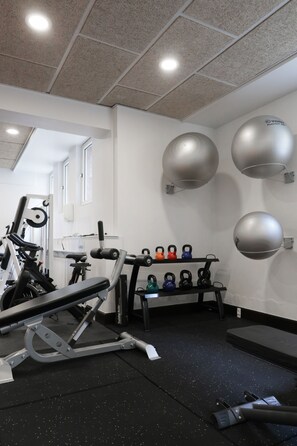 A gym with exercise equipment, kettlebells, and wall-mounted medicine balls. - Hotel Phønix (Aalborg)