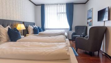 A hotel room with two beds, a chair, a TV, and a window with curtains.