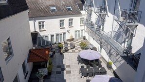 A courtyard with outdoor seating, a fire escape, and a building with a tiled roof. - Hotel Phønix (Aalborg)