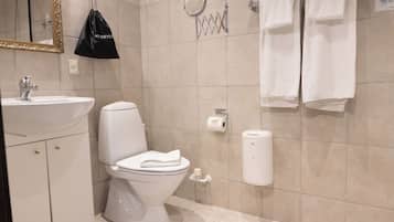Un baño con inodoro, lavabo, perchero y una bolsa colgada en la pared.