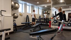 A gym with exercise equipment, a mirror, and windows. - Hotel Phønix (Aalborg)