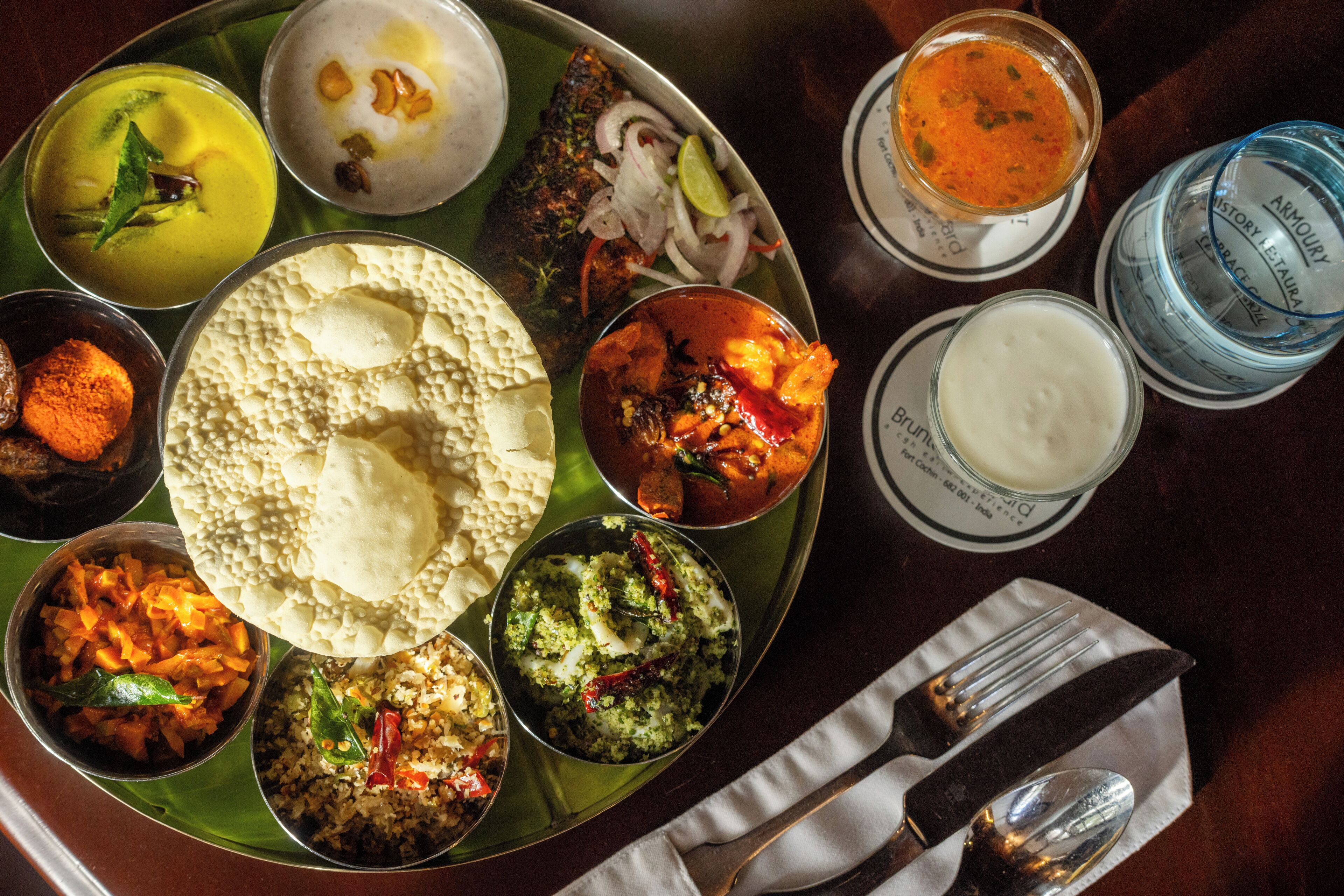 A variety of dishes on a metal tray with a cloth napkin and cutlery.