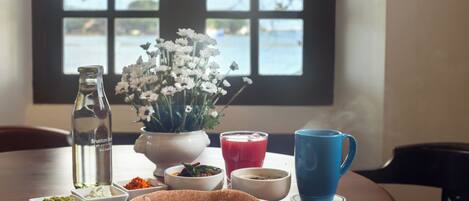 A table with a traditional meal, including a dosa, various condiments, and a blue cup.