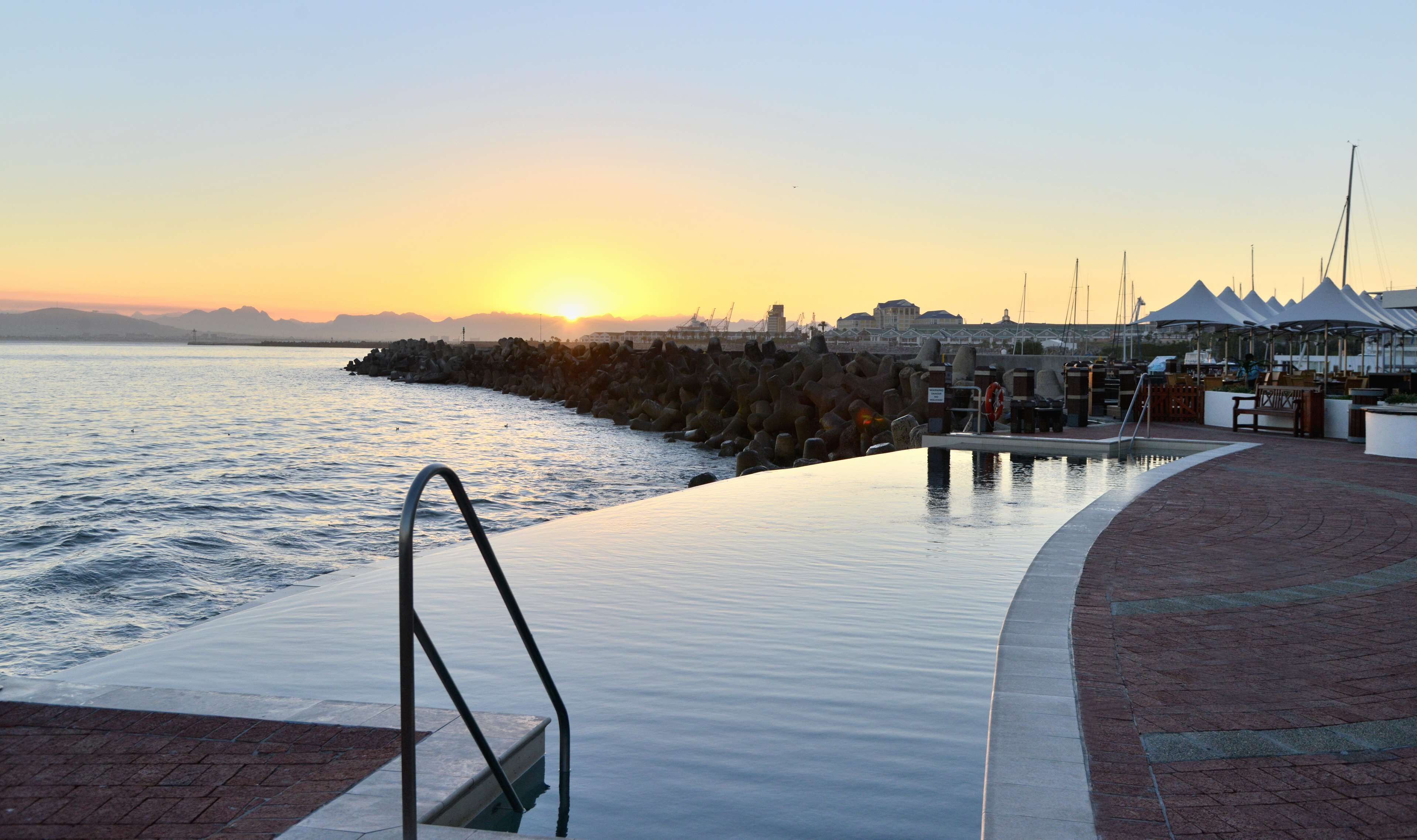 An infinity pool with a view of the sea and a sunset.