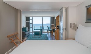 A hotel room with a large bed, a seating area with a view of the sea, and a balcony with a railing. - Radisson Collection Hotel, Waterfront Cape Town (Cape Town)