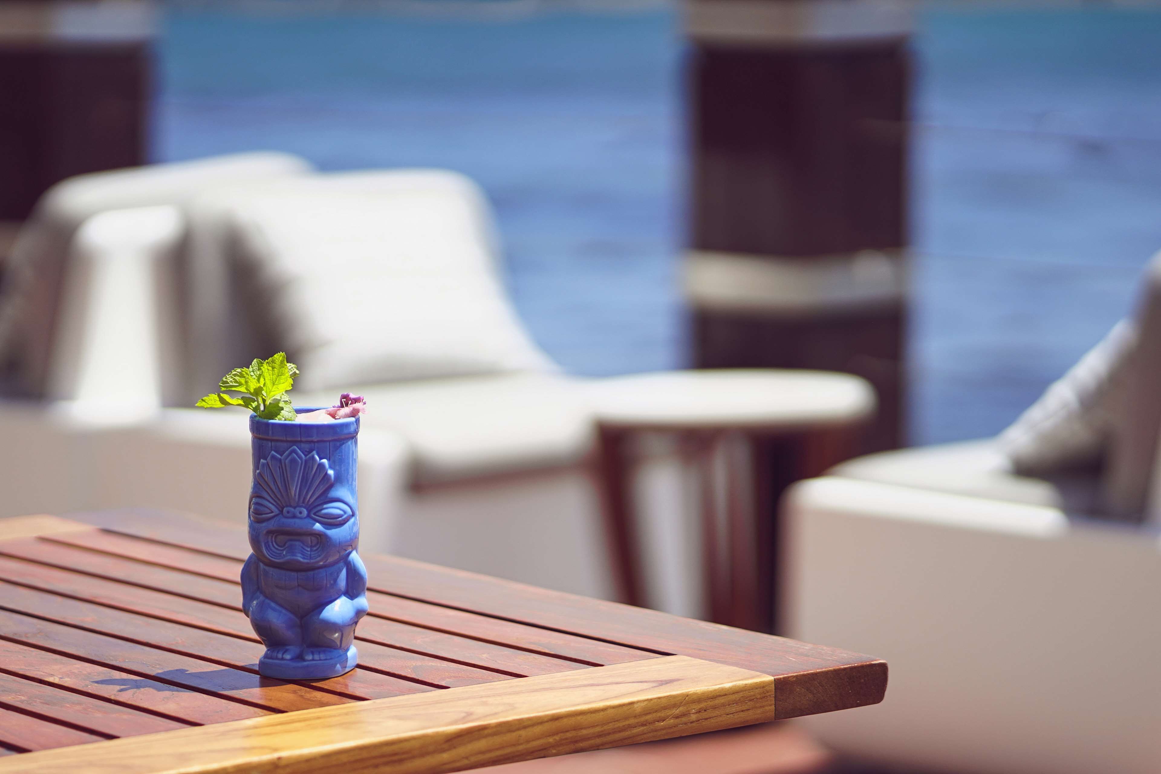 Une statue tiki sur une table en bois, avec l’océan en toile de fond.
