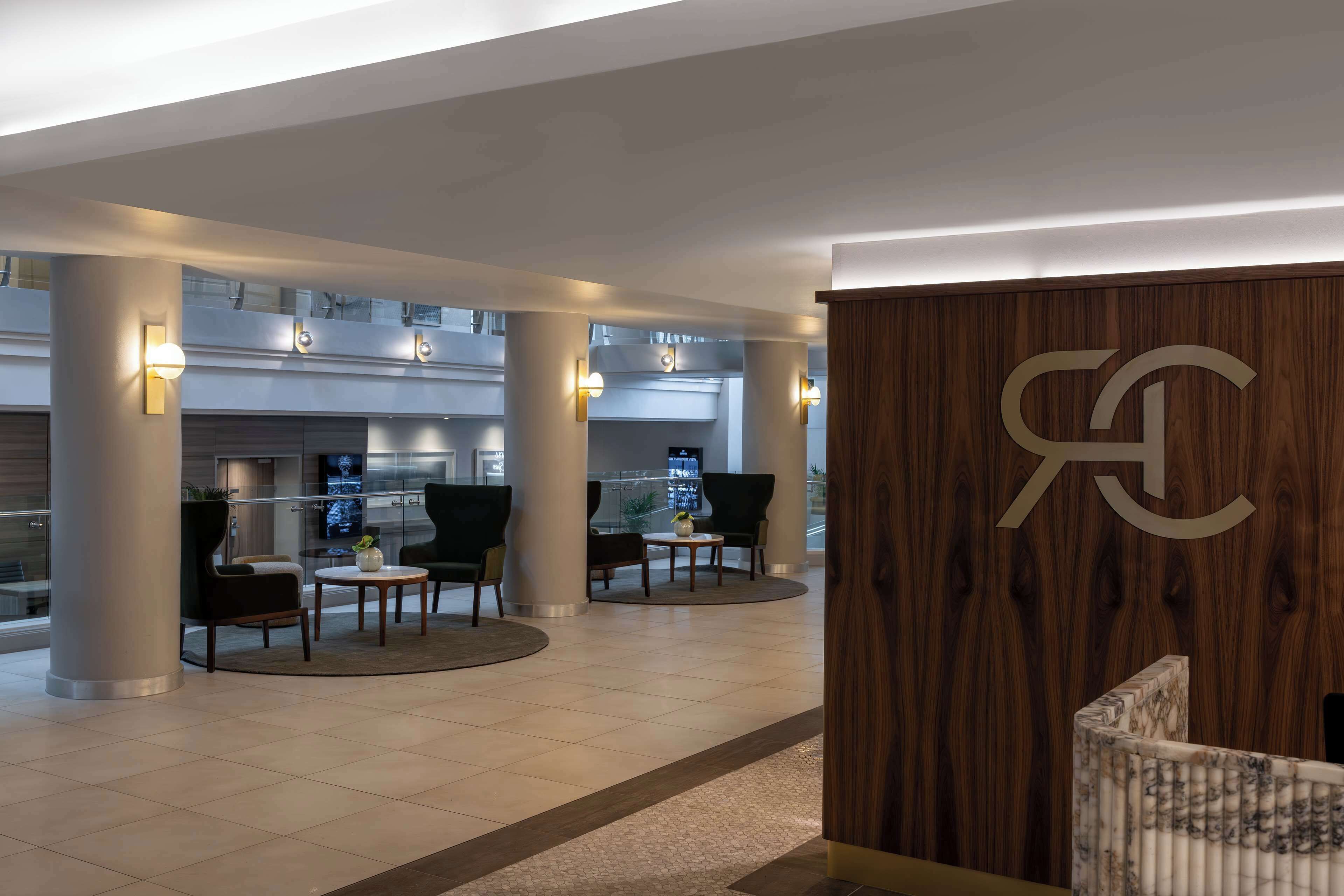 Een moderne lobby met een receptiebalie, een zithoek en een groot scherm dat content toont.