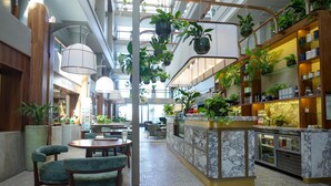 A spacious lobby with a central bar area, seating arrangements, and hanging plants. - Radisson Collection Hotel, Waterfront Cape Town (Cape Town)