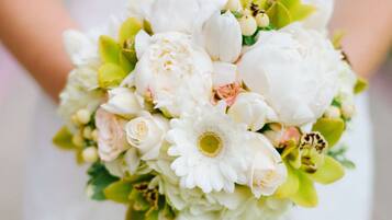 Un ramo de flores sostenido por una persona con un vestido blanco.