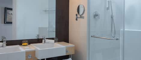 Un baño moderno con dos lavamanos, cabina de ducha de vidrio y un espejo grande.