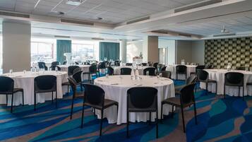 A conference room with round tables, chairs, and a carpeted floor.