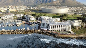 A coastal cityscape with a marina, buildings, and mountains in the background.