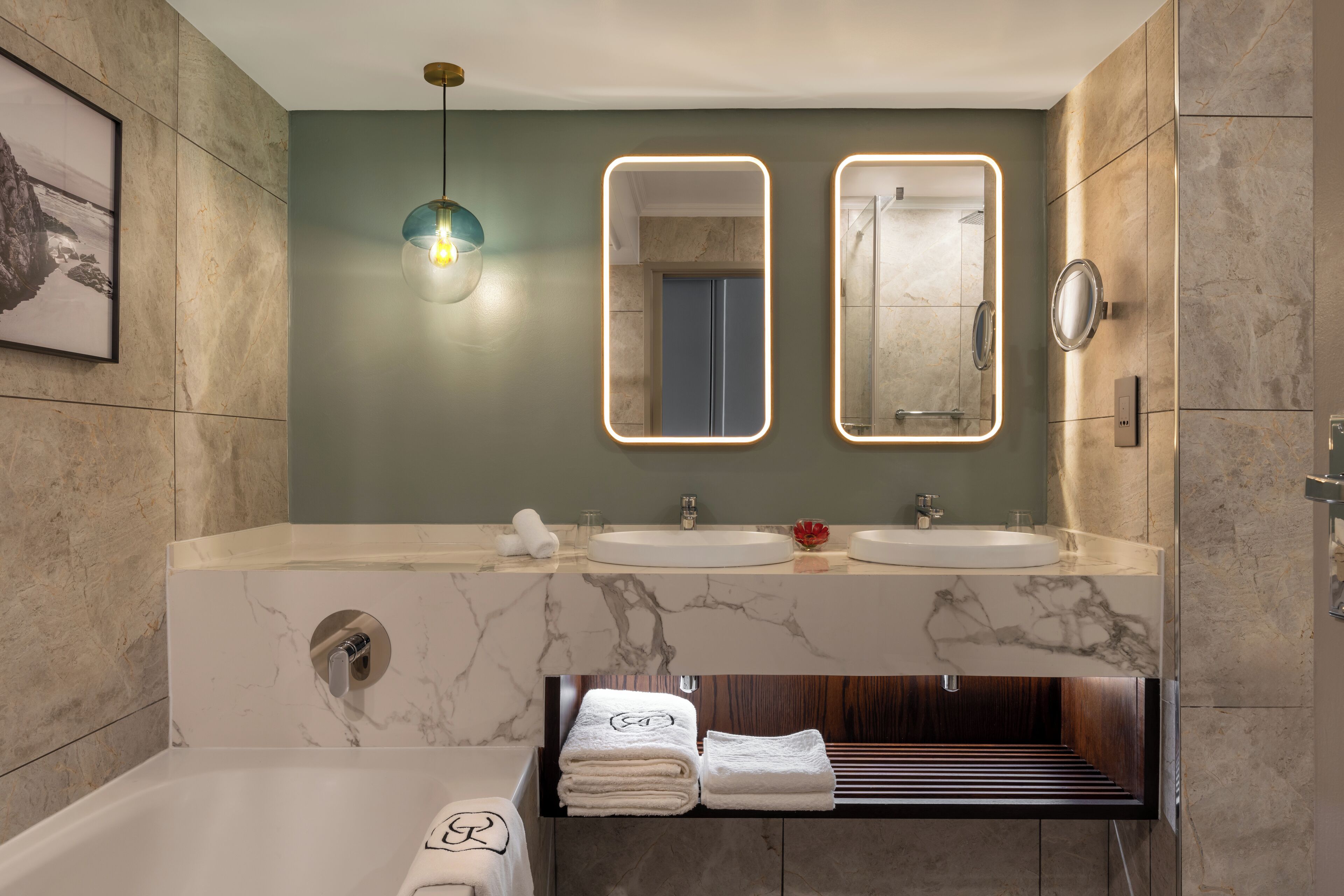 Un baño moderno con dos lavamanos, un espejo grande y un banco empotrado con toallas.