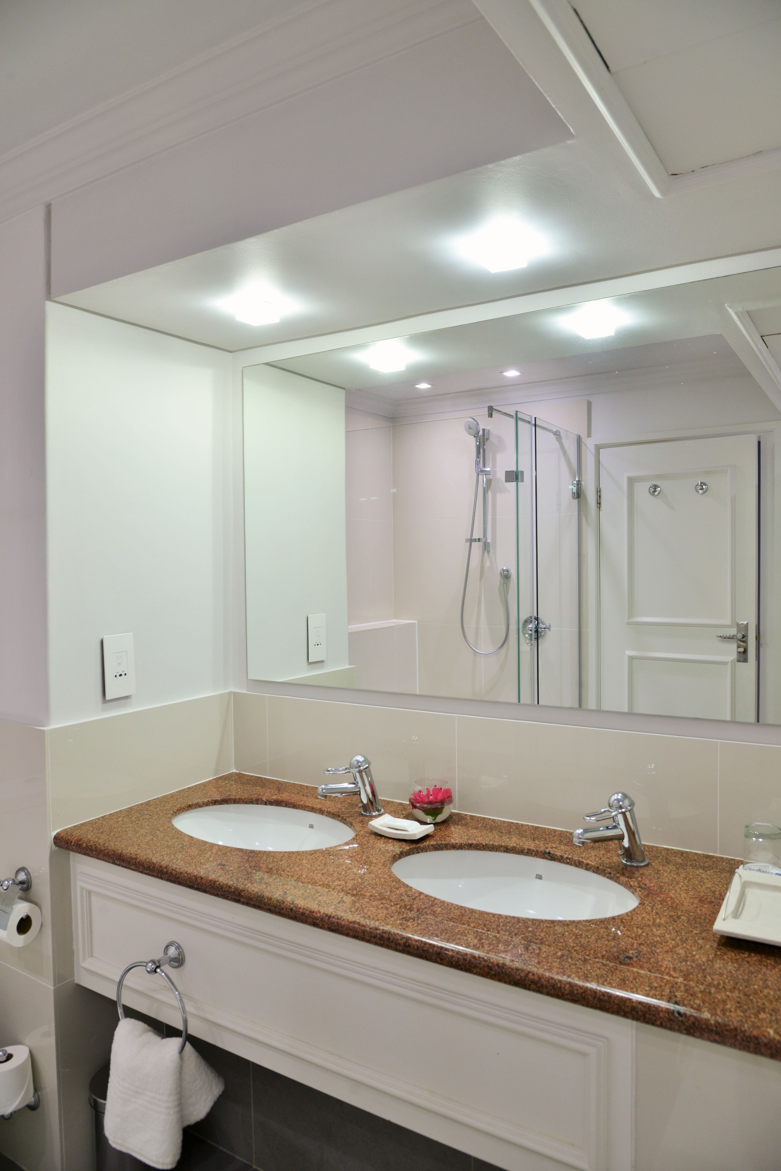 A bathroom with two sinks, a large mirror, and a shower.