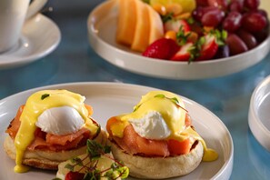 A breakfast setting with eggs Benedict and a fruit bowl. - Radisson Collection Hotel, Waterfront Cape Town (Cape Town)