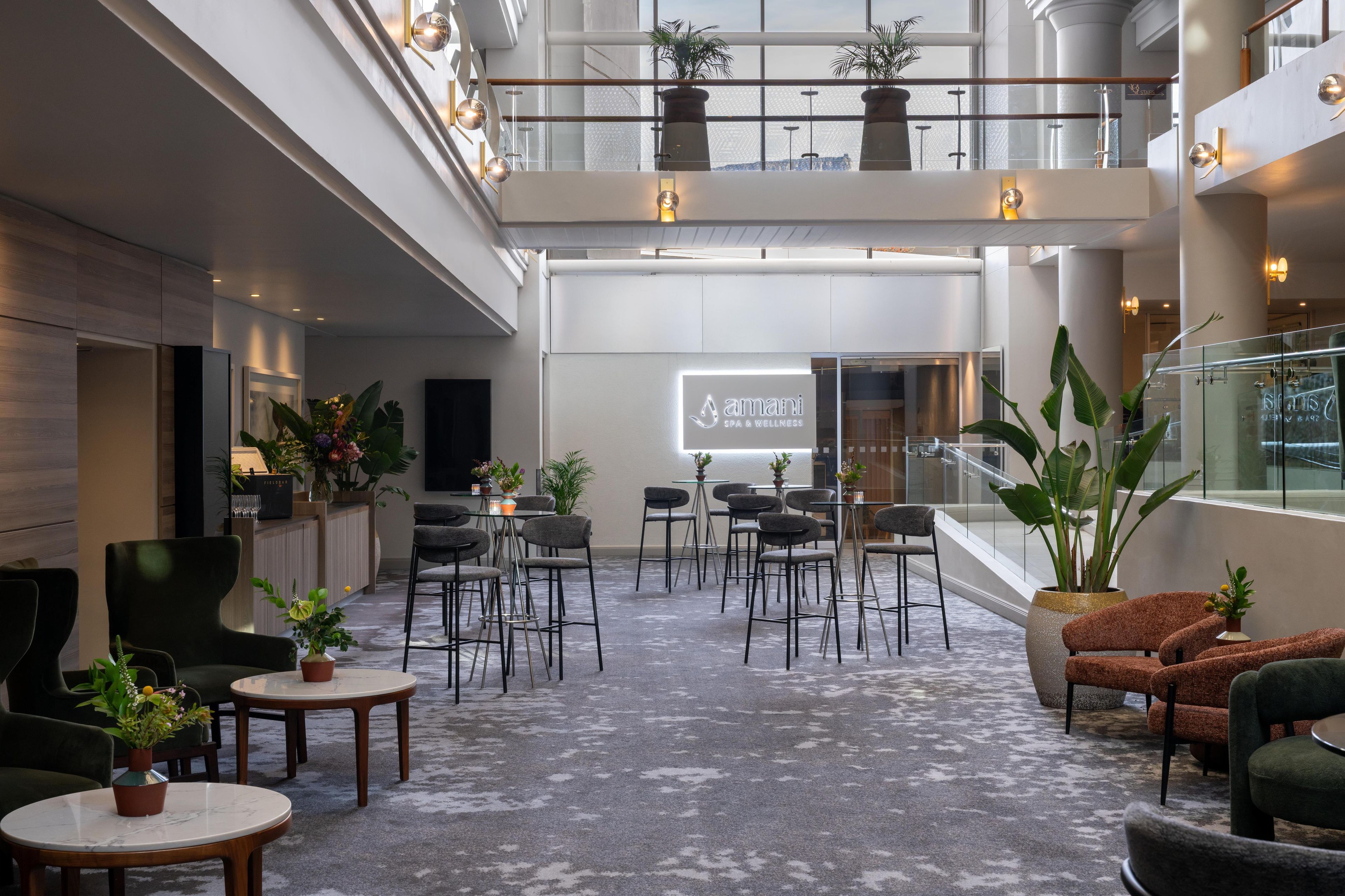 A spacious indoor area with multiple seating arrangements, including tables and chairs, and a central area with a projection screen.