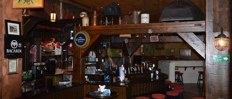Zona de bar con taburetes, una barra y un letrero que dice 'Corona Extra'.