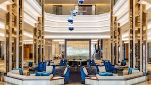 A spacious lobby with a central seating area, a piano, and a high ceiling with hanging lights. - The Diplomat Radisson BLU Hotel, Residence & Spa (Manama)
