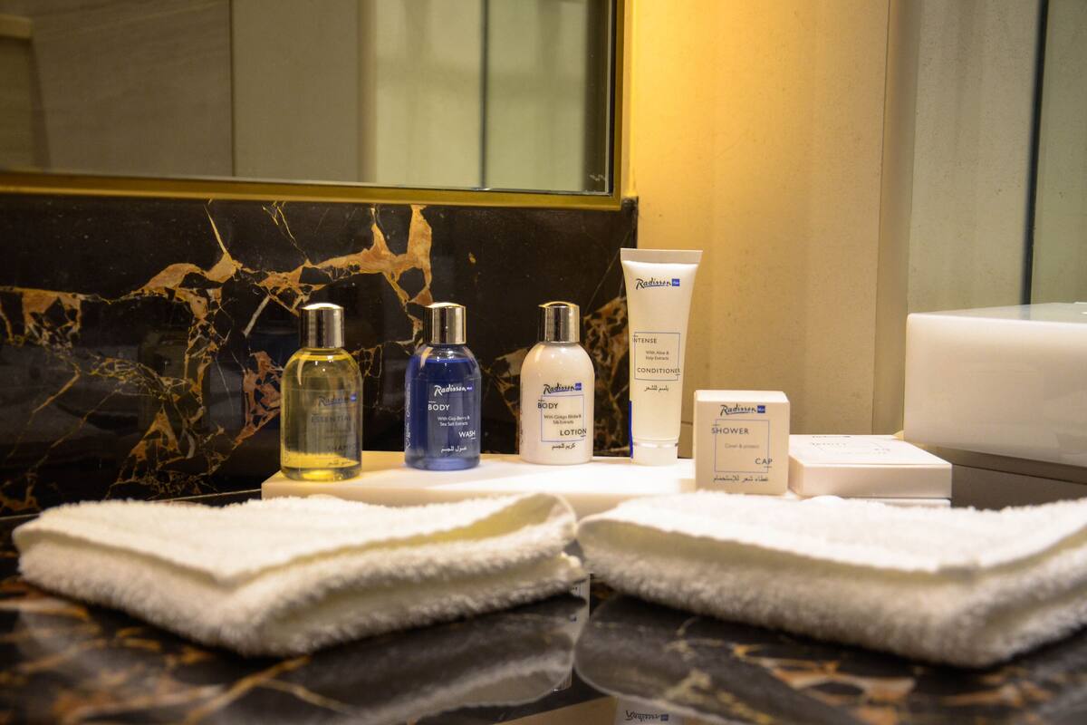A bathroom vanity with toiletries including body wash, lotion, and a shower cap.