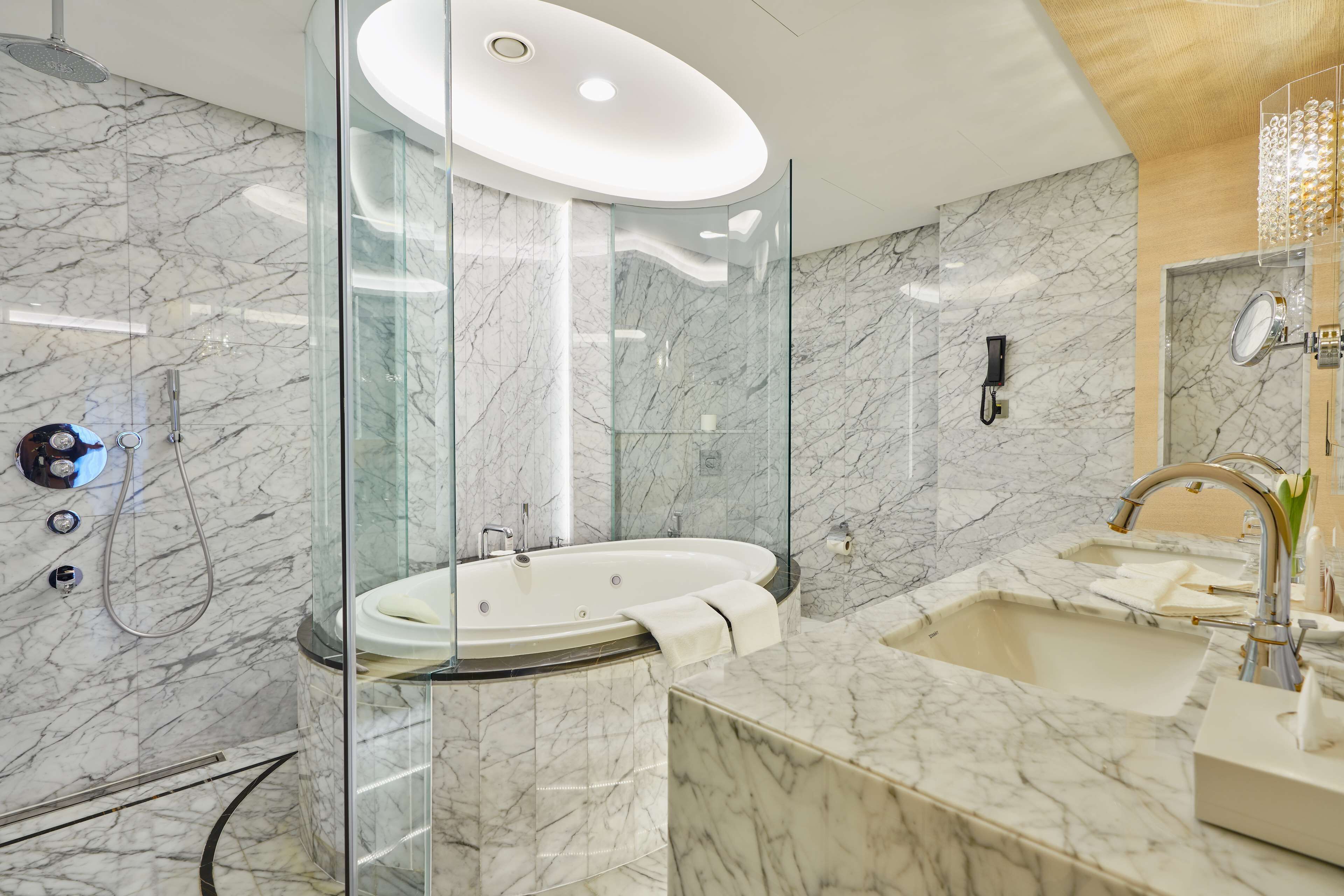 Un baño moderno con ducha envuelta en vidrio, una bañera independiente y un amplio tocador con lavamanos.