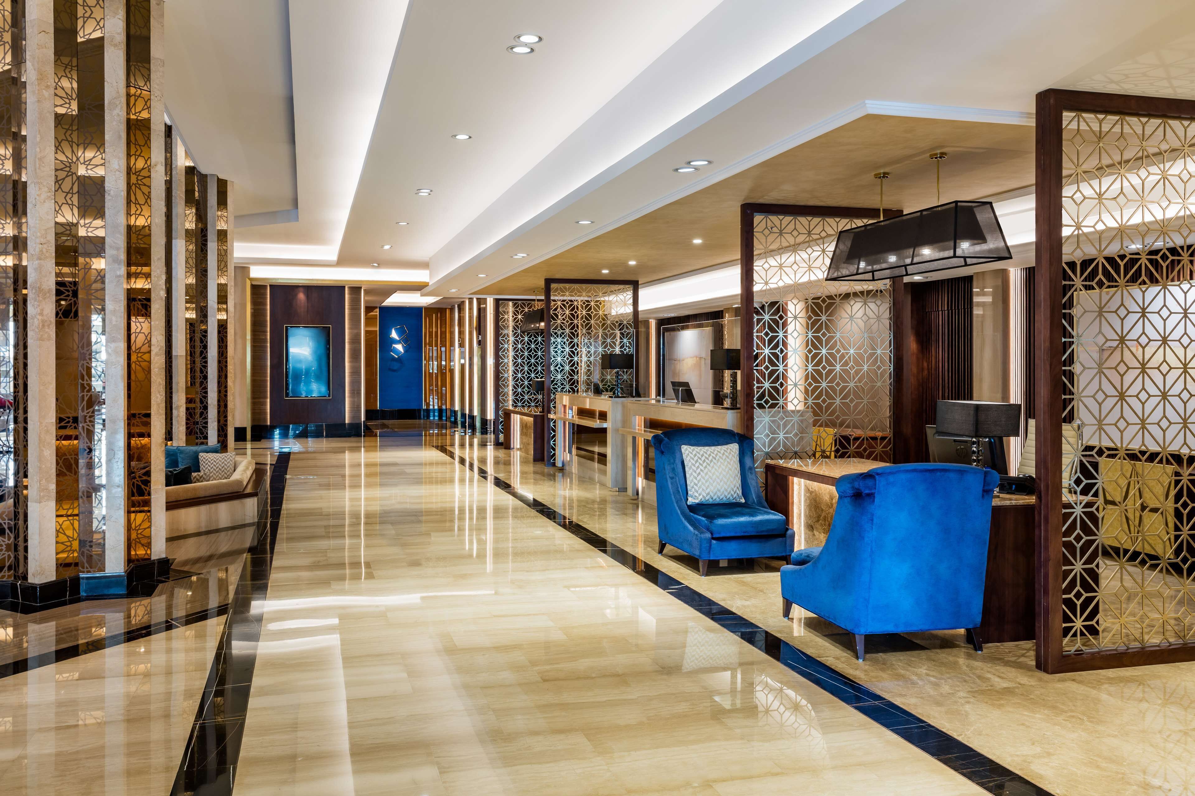 A spacious lobby with a polished floor, seating areas, and decorative panels.